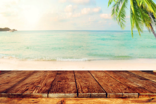 Top of wood table on blurred sea with coconut tree background - Empty ready for your product display montage. Concept of beach in summer. vintage color tone