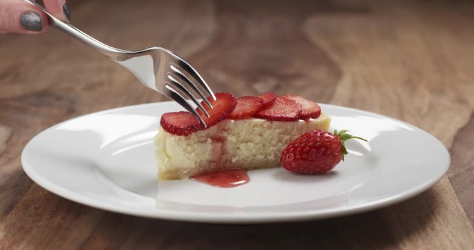 Slow motion of trying to eat strawberry cheesecake with fork on wood table, 4k 60fps prores footage