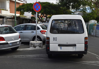 Cars parked on the street close to a sign
