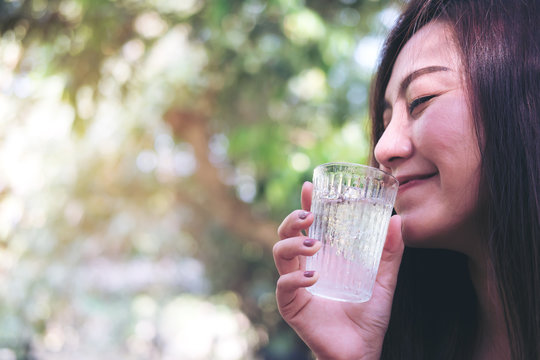 A woman holding and drinking cold water  with blur nature background