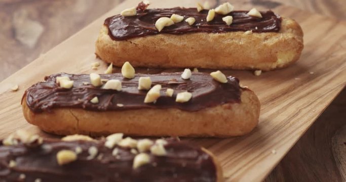 Slow motion of backward fly over eclairs with hazelnuts on wood board, 4k 60fps prores footage
