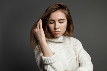 Girl model in white sweater on a gray background.