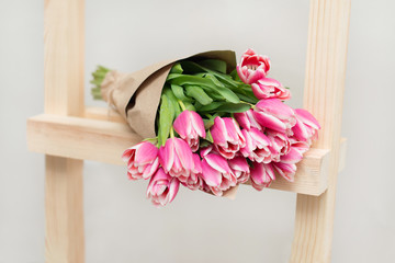 Beautiful bouquet of tulips on wooden stairs. A light gray background.
