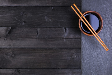 Background for sushi. Soy sauce, chopsticks on black stone. Top view with copy space