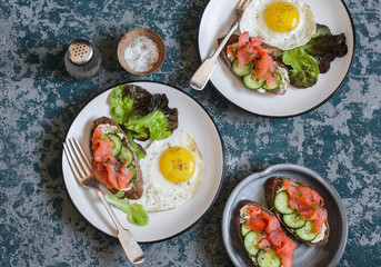 Fried egg and salmon cream cheese sandwich - delicious breakfast, brunch or snack. On wooden background, top view. Flat lay