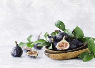 dark blue Fresh figs in a wooden bowl on a white marble table, selective focus