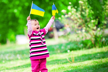 Fototapeta na wymiar little girl on the grass with the flags of Ukraine
