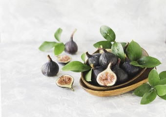 dark blue Fresh figs in a wooden bowl on a white marble table, selective focus