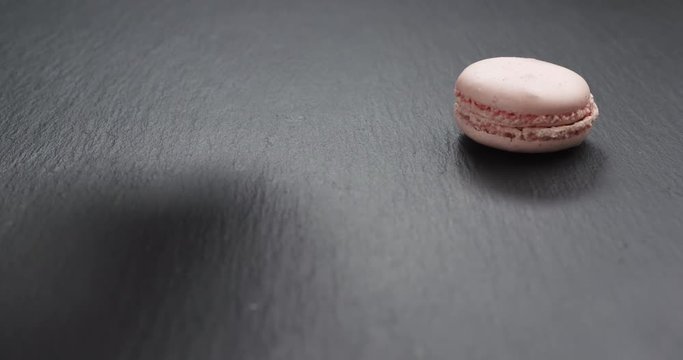 Slow motion of man hand bring pink macaroons on slate board, 4k 60fps prores footage