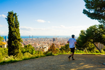 young man jogging with view of barcelona and sagrada familia in summer day