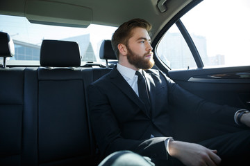 Fototapeta na wymiar Man in suit sitting at the back seat of car