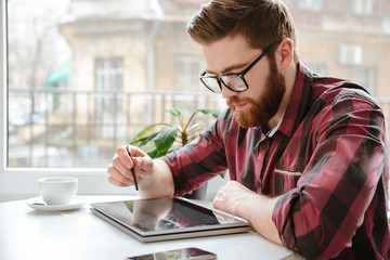 Amazing bearded young man using tablet computer.