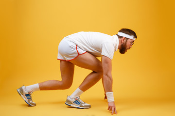 Side view of sportsman in sunglasses preparing to run