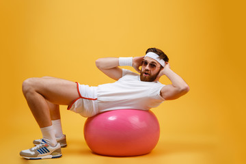 Side view sportsman lying on fitness ball and looking camera
