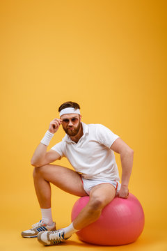 Vertical image of sportsman sitting on fitness ball