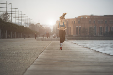 a woman jogging by the seaside in urban city environment