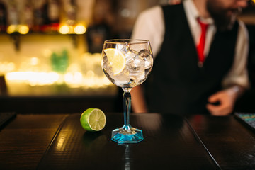Alcoholic cocktail and lime on wooden counter