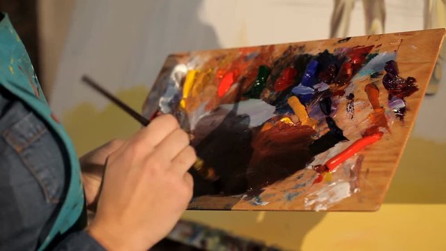 Young artist mixes bright paint on the palette