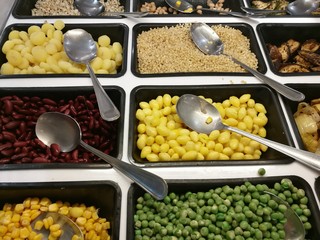 Salad bar with various fresh vegetables selection and spoon,corn, green peas,lotus seeds,red yellow bean,waternut,eggplant,aubergine,onion, focus-on-foreground with blur background