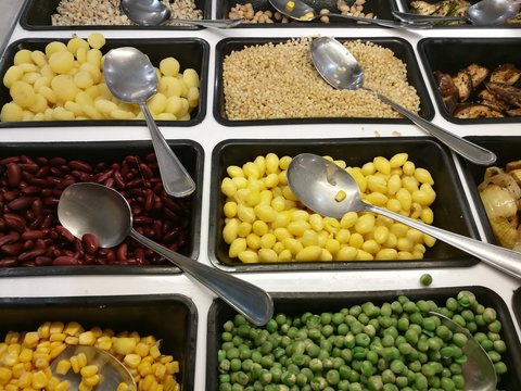 Salad bar with various fresh vegetables selection and spoon,corn, green peas,lotus seeds,red yellow bean,waternut,eggplant,aubergine,onion, focus-on-foreground with blur background