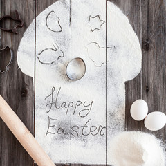 Symbolic image Easter cake with utensils on a dark wooden background. Rolling pin, cookie cutters cutting, eggs, flour