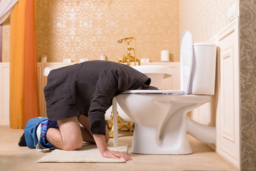 Man with pants down sick in the toilet bowl