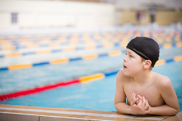 Portrait of a cute little boy ready to dive in the sport swimming pool. Indoors. Sport activities for children. Training for competition.