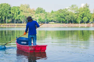 Foto op Canvas a man on the boat cleaning swamp in the park. © thithawat