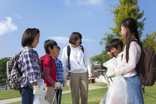 School children and female teacher holding bags for recycling