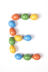 Colorful Easter eggs composition on a white background. Letter E. Green, red, yellow and blue colors.