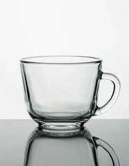 Empty glass mug on a reflective surface. Product photography