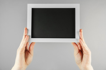 Female hands holding blackboard on color background