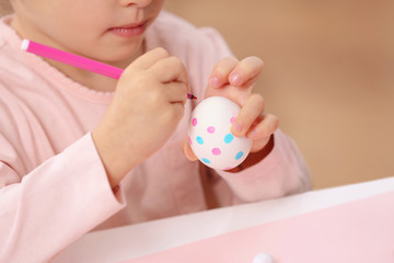 Naklejka premium Little girl decorating Easter egg