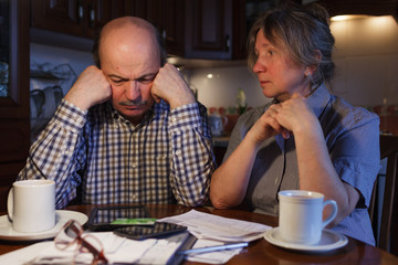 The elderly couple considers their family budget. Problems with money. They are trying to find a solution.