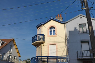Petite maison avec balcon, ciel bleu, fils électrqiues