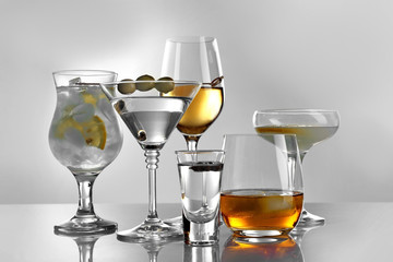 Glasses of wine and spirits on light background