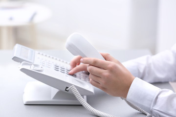 Hands of man dialing telephone number in office