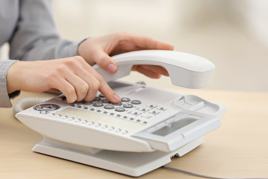 Woman dialing number on telephone in office
