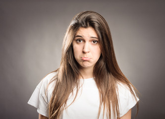 young girl with sad expression on a gray background