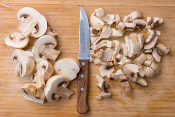 Slicing champignons on a wooden chopping board