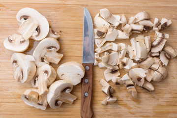 Slicing champignons on a wooden chopping board