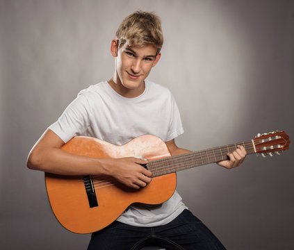 young man with acoustic guitar on a gray background