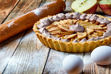 Beautiful classic apple tart with meringue. American / French pie with apples and whipped egg whites. Chocolate meringue on the cake. Baking from short pastry. Kitchen table in flour. 
