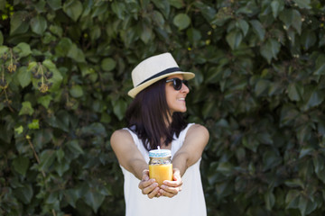 beautiful young woman enjoying an orange juice outdoors. Green background
