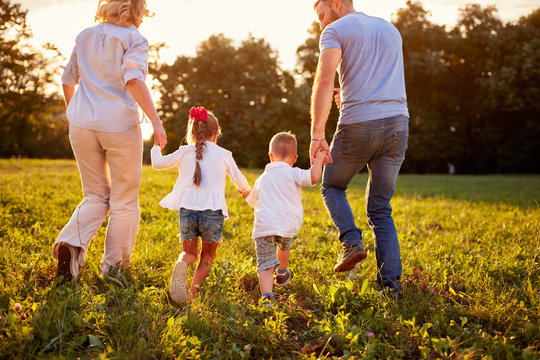 Parents With Children Walking In Nature, Back View