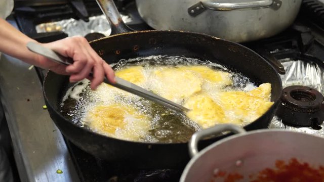 A female cook frying some chicken cutlets in the oil in Italy, 4K