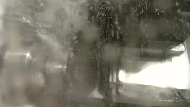 Action of lathe machine. Splashes of liquid. Water as a coolant.
