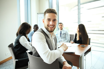 Businessman with colleagues in the background in office.