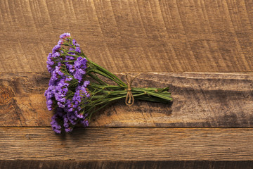 Bundle of small purple flowers on wood background