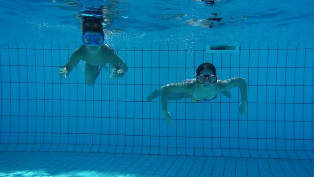 Boy and girl in swimming pool swim underwater